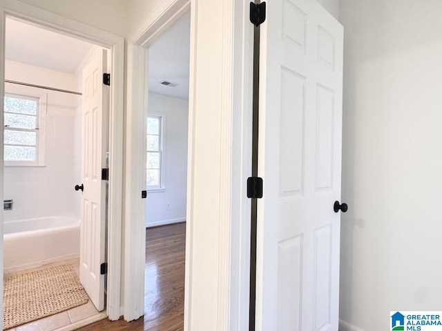 full bath featuring bathtub / shower combination, wood finished floors, visible vents, and baseboards