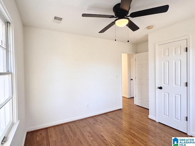 unfurnished bedroom with ceiling fan, wood finished floors, visible vents, and baseboards