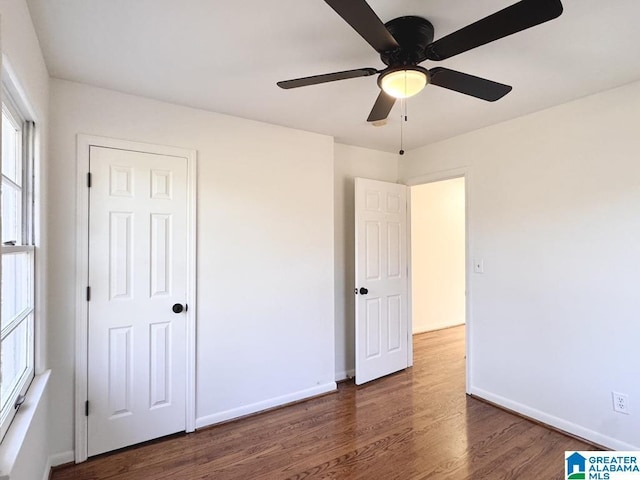 unfurnished bedroom with a ceiling fan, baseboards, and wood finished floors