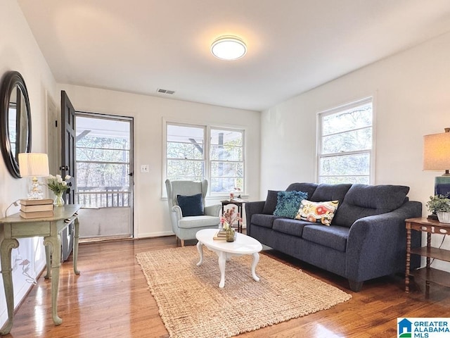 living room with visible vents, light wood finished floors, and a wealth of natural light