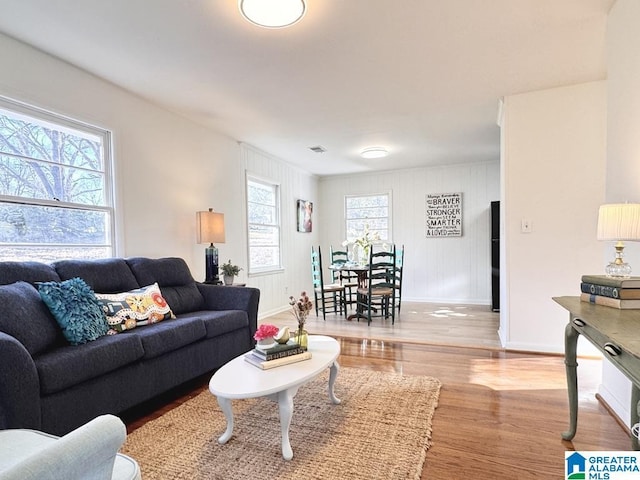 living room with visible vents, baseboards, and wood finished floors