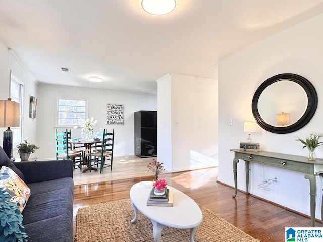 living area with wood finished floors, visible vents, and baseboards