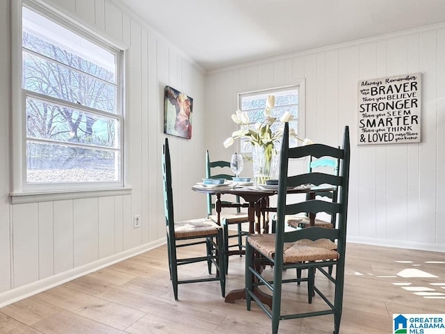 dining area featuring light wood-style flooring, baseboards, and crown molding