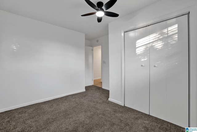 unfurnished bedroom with a closet, dark carpet, a ceiling fan, and baseboards