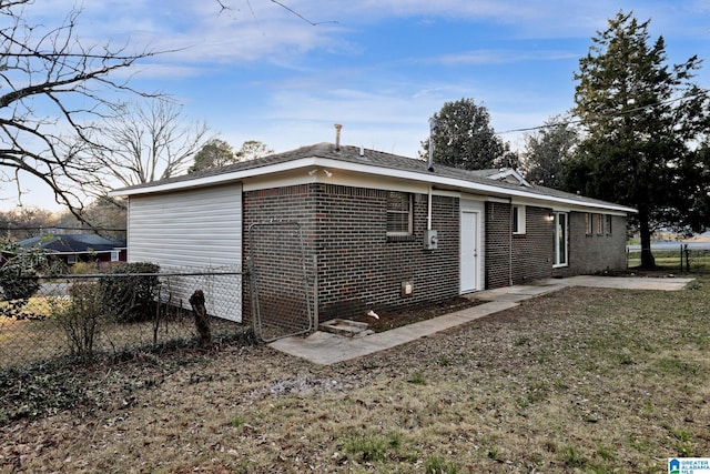 view of side of property with fence, a lawn, and brick siding