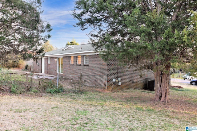 exterior space featuring a yard, cooling unit, brick siding, and fence