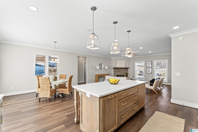 kitchen featuring dark wood-style floors, ornamental molding, a kitchen island, and baseboards