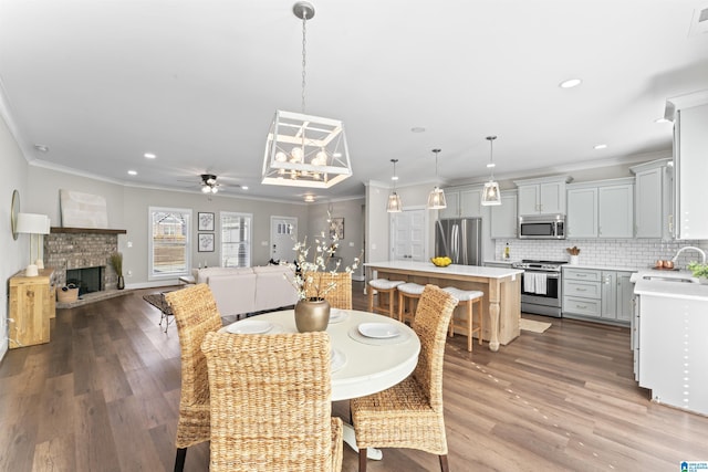 dining area with ornamental molding, recessed lighting, a fireplace, and wood finished floors