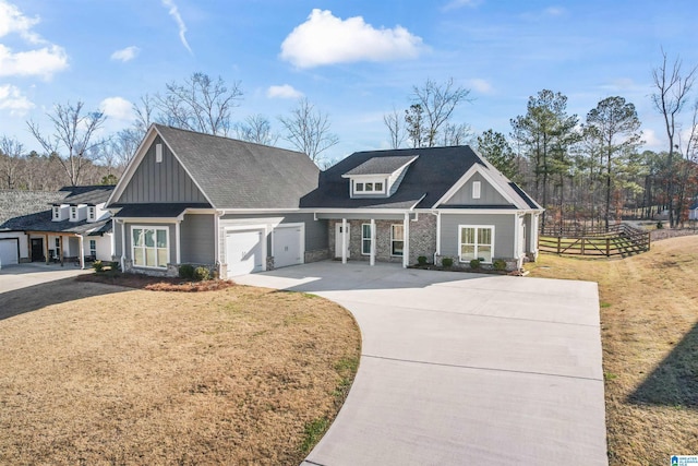 view of front of property with concrete driveway, board and batten siding, a front yard, fence, and a garage