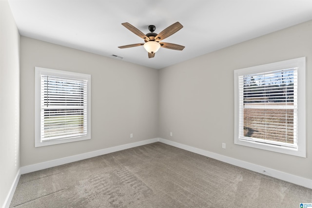 unfurnished room featuring a wealth of natural light, carpet, visible vents, and baseboards