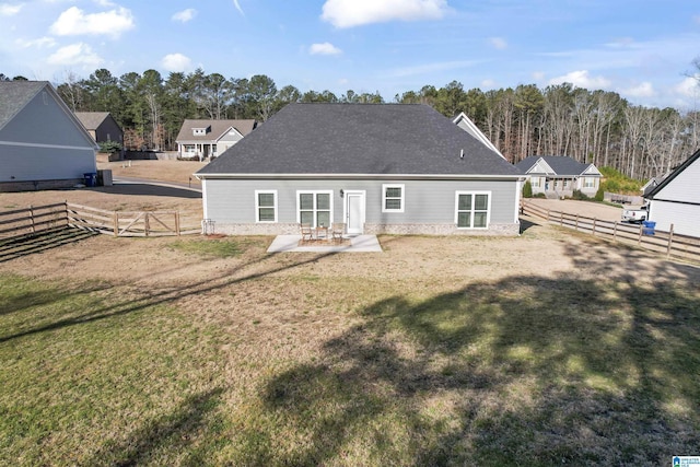 rear view of house with a yard, roof with shingles, a patio area, and fence