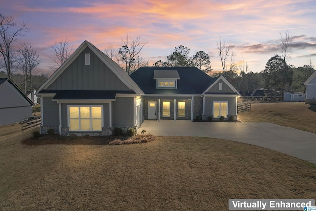 craftsman-style home with stone siding, board and batten siding, and a yard