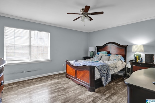 bedroom with ceiling fan, crown molding, baseboards, and wood finished floors