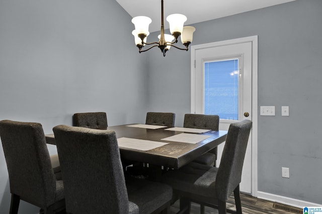 dining space featuring baseboards, wood finished floors, visible vents, and an inviting chandelier