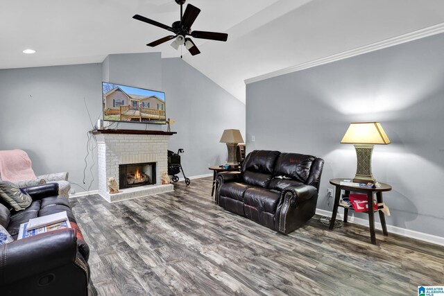 living room featuring ceiling fan, wood finished floors, baseboards, vaulted ceiling, and a brick fireplace