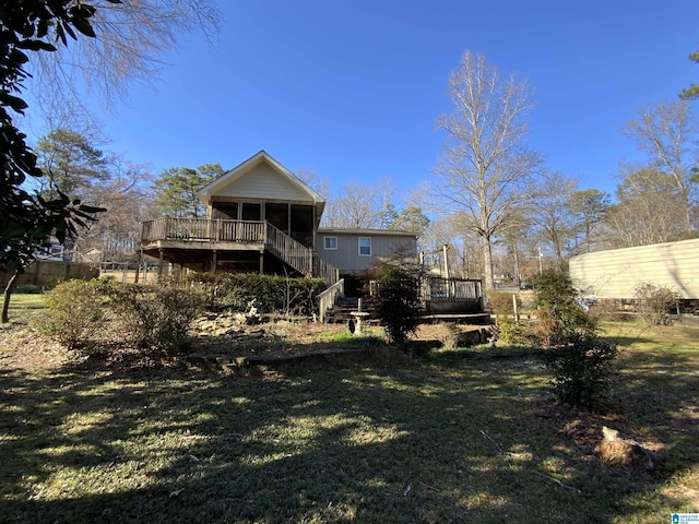 back of house featuring a deck, a lawn, stairway, and a sunroom