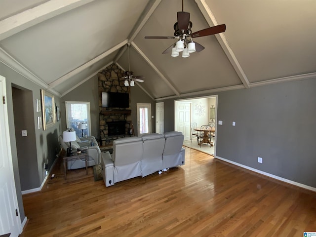 unfurnished living room with baseboards, a stone fireplace, lofted ceiling with beams, and wood finished floors