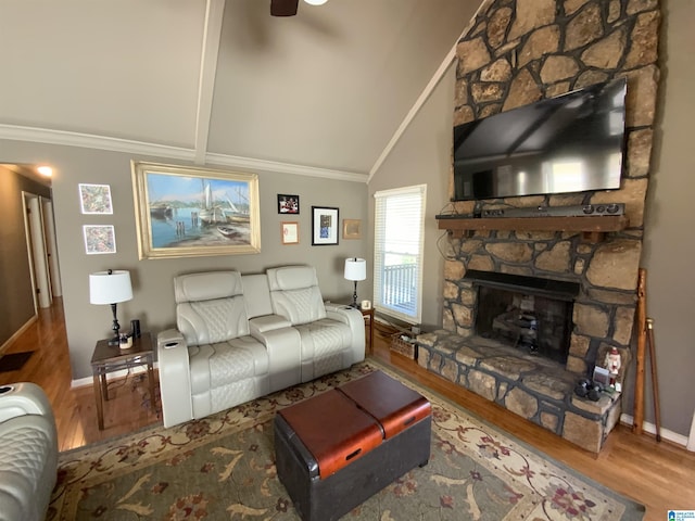 living room featuring baseboards, ornamental molding, wood finished floors, a stone fireplace, and high vaulted ceiling