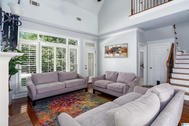 living area featuring high vaulted ceiling, visible vents, stairway, and wood finished floors