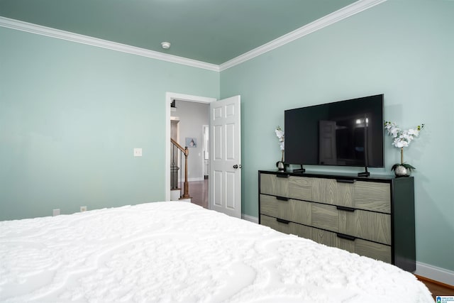 bedroom with ornamental molding, baseboards, and wood finished floors