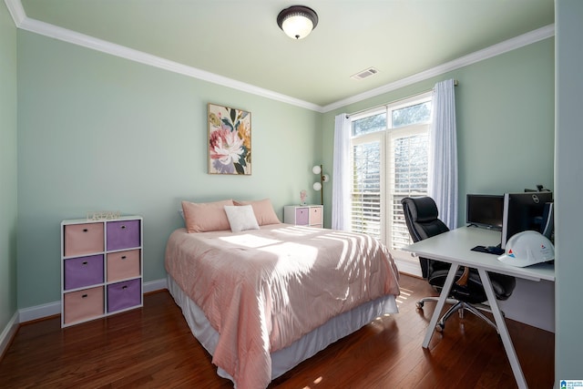 bedroom with visible vents, crown molding, baseboards, and wood finished floors