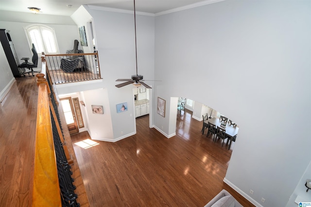 living area with baseboards, wood finished floors, and ornamental molding