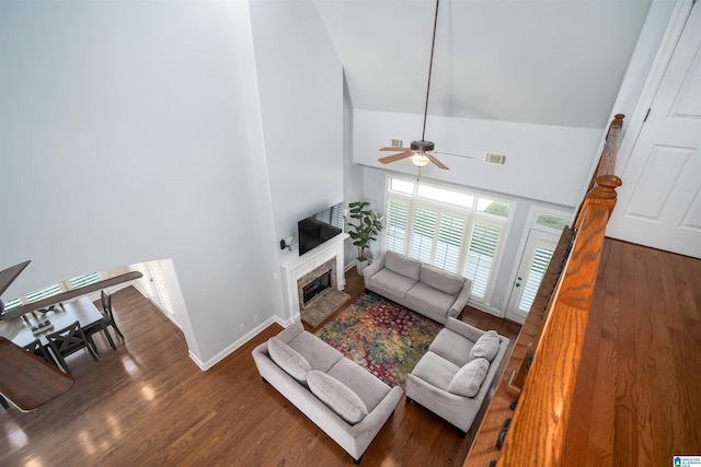 living area featuring baseboards, visible vents, wood finished floors, a fireplace, and high vaulted ceiling