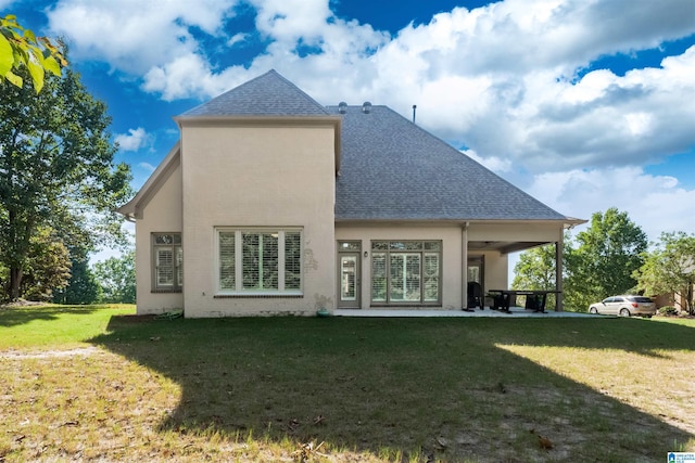 back of property featuring a yard, a patio, roof with shingles, and stucco siding