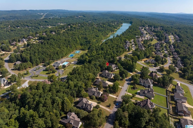 birds eye view of property featuring a water view and a wooded view