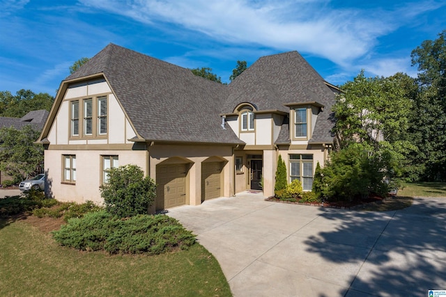 view of front facade with an attached garage, roof with shingles, concrete driveway, and stucco siding