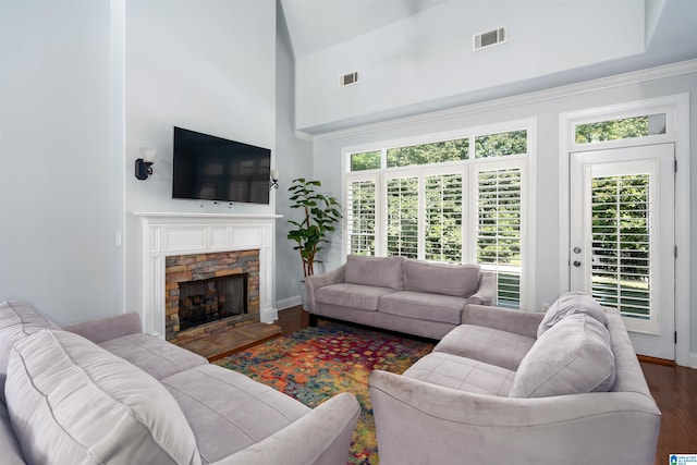 living area with a high ceiling, a fireplace, wood finished floors, visible vents, and baseboards