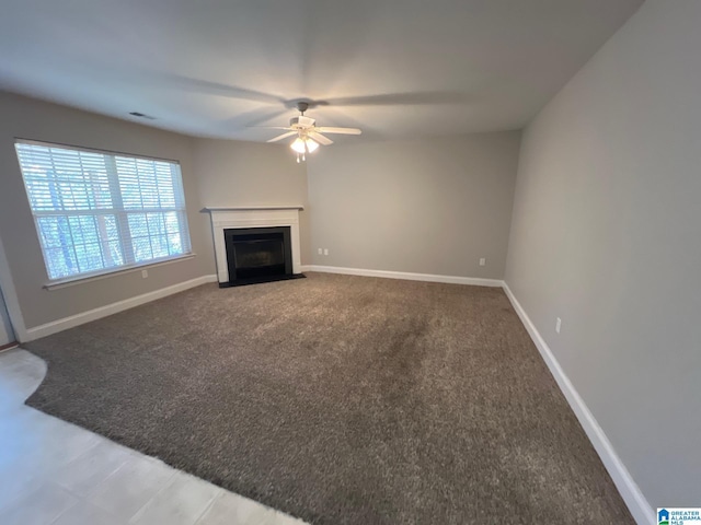 unfurnished living room with visible vents, baseboards, a ceiling fan, a fireplace with flush hearth, and carpet floors