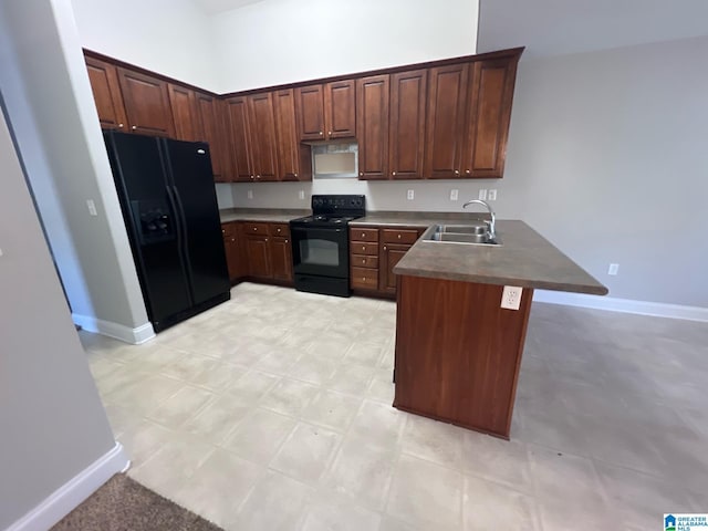 kitchen featuring dark countertops, a sink, black appliances, a peninsula, and baseboards