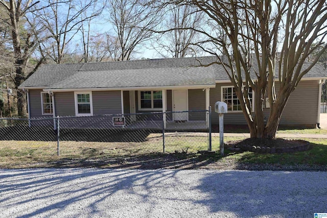 ranch-style house with a fenced front yard and roof with shingles