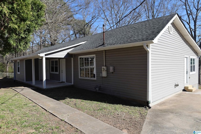 view of side of property featuring a shingled roof and a lawn