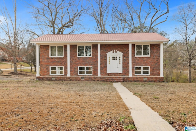 split foyer home featuring metal roof, a front lawn, and brick siding