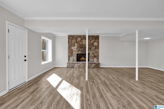 unfurnished living room featuring baseboards, a fireplace, wood finished floors, and crown molding