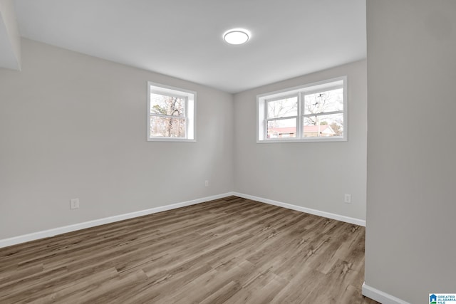 spare room with baseboards and wood finished floors