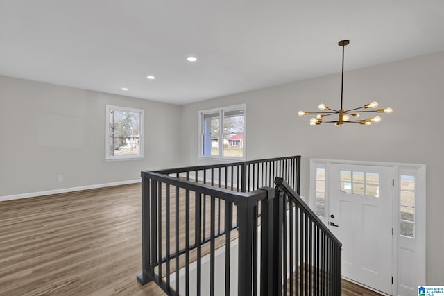 stairway with a notable chandelier, baseboards, wood finished floors, and recessed lighting