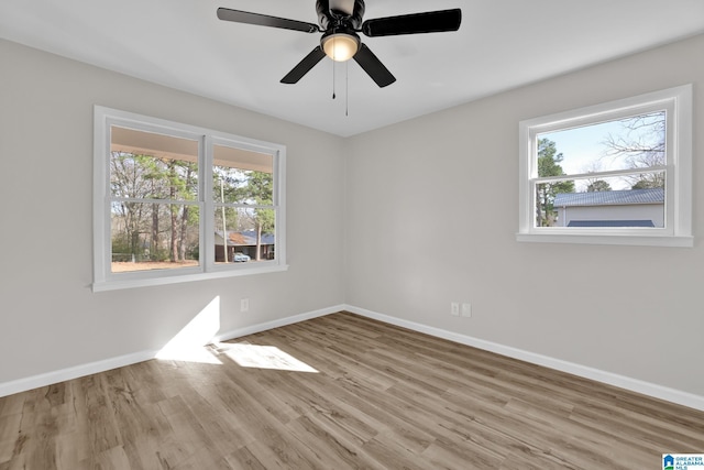 spare room featuring baseboards, wood finished floors, and a healthy amount of sunlight