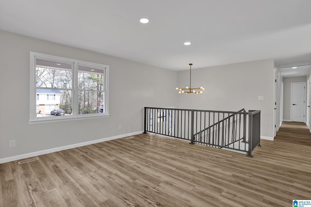 unfurnished room featuring wood finished floors, visible vents, and baseboards