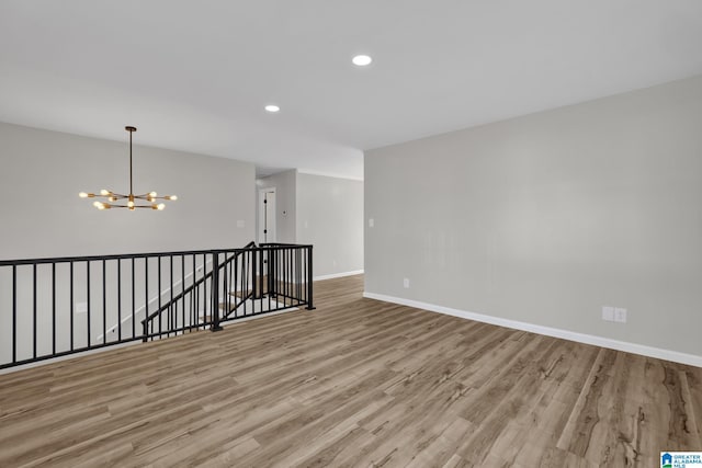 unfurnished room featuring baseboards, a chandelier, wood finished floors, and recessed lighting