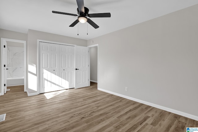 unfurnished bedroom with a closet, visible vents, a ceiling fan, wood finished floors, and baseboards