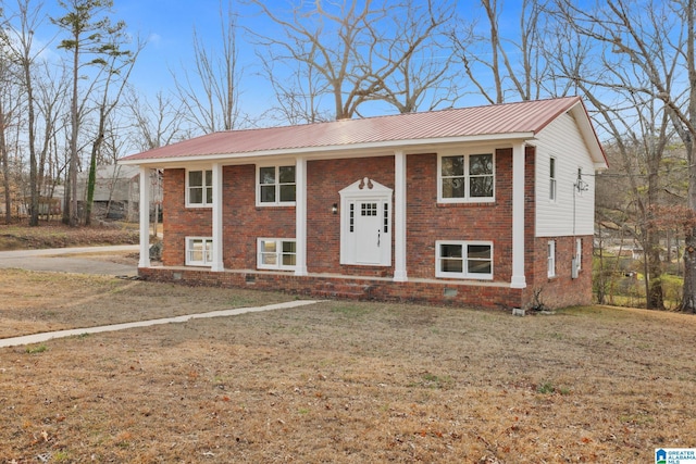 raised ranch featuring a front yard, metal roof, and brick siding