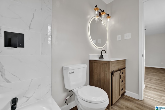 bathroom featuring toilet, baseboards, wood finished floors, and vanity