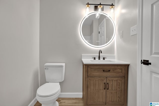 half bathroom with toilet, baseboards, wood finished floors, and vanity