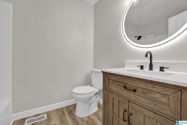 bathroom featuring toilet, wood finished floors, vanity, visible vents, and baseboards