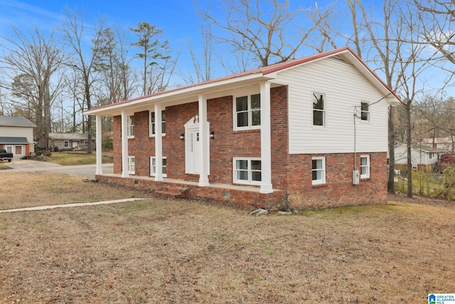 bi-level home featuring brick siding, a front yard, and fence