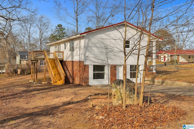 rear view of house featuring brick siding, a wooden deck, and stairs