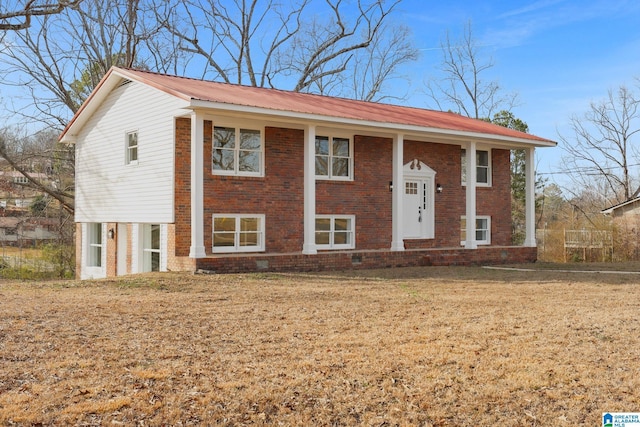 split foyer home with metal roof, brick siding, and a front lawn